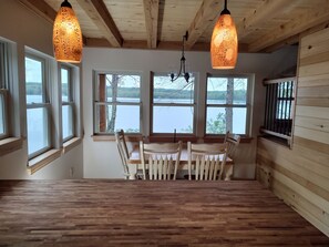 Een eetruimte met houten meubels, grote ramen en hangende吊灯
