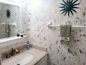 Ein Badezimmer mit Waschbecken, Handtuchhalter und Wandbild.