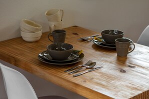 A wooden table with various bowls and cups, some stacked, and a pair of forks and spoons on the table. - Vale Mandaçaia (Urubici)