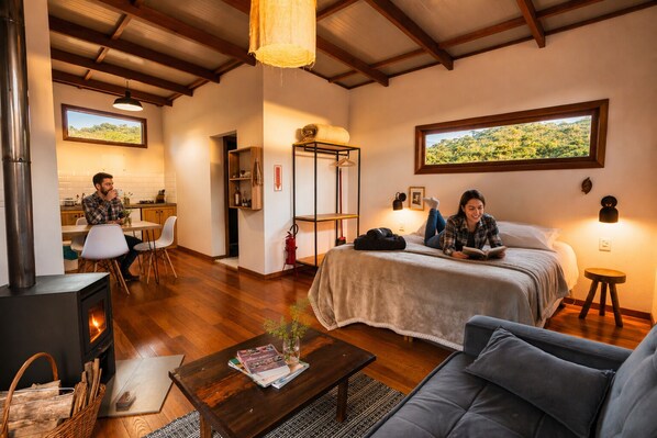 A cozy room with a bed, a sofa, a dining area, and a fireplace.
