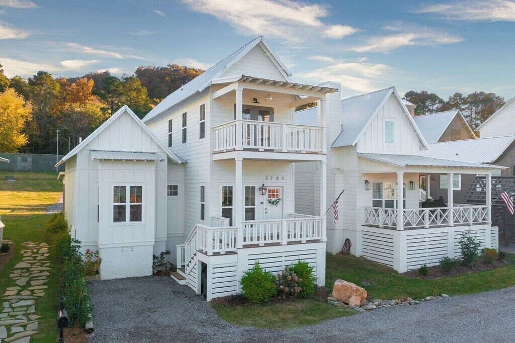 A white two-story house with a balcony, a garage, and a front porch.