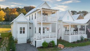 A white two-story house with a balcony, a garage, and a front porch. - My Happy Place at River Rocks Plantation (Guntersville)