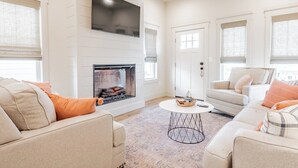 A living room with a fireplace, sofas, a TV, and a door. - My Happy Place at River Rocks Plantation (Guntersville)