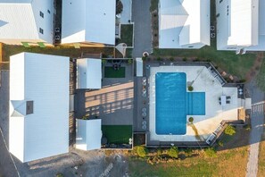 Vista aérea de um bairro residencial com várias casas brancas, uma piscina e uma área de pátio.