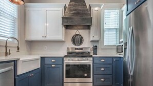 A kitchen with white cabinets, a stainless steel range hood, and a built-in oven.