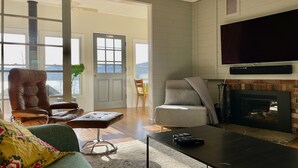 Una sala de estar con chimenea, televisor grande y vistas al exterior a través de la puerta.
