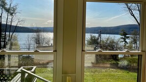 Una habitación con dos ventanas que dan a un lago y colinas.