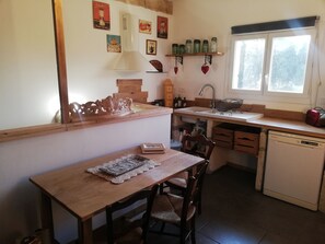 Una cocina funcional con una mesa de madera, sillas, un lavabo y un ventanal.