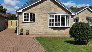 A stone house with a gabled roof, a small front garden, and a paved driveway. - 17 Costa Way (Pickering)