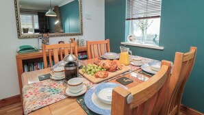 A dining area with a wooden table set for breakfast, including plates, cups, a coffee pot, and a fruit platter. - 17 Costa Way (Pickering)