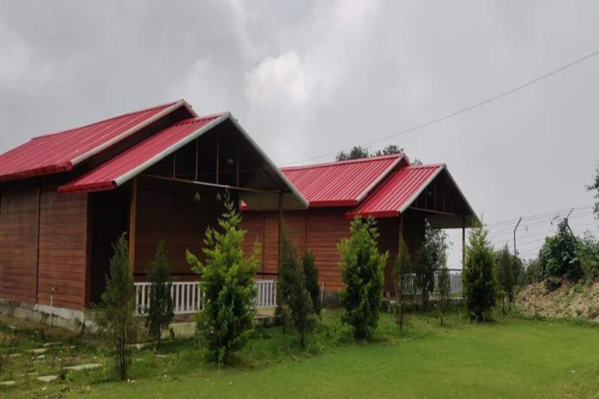 Ein zweistöckiges Holzhaus mit rotem Dach und überdachter Veranda.