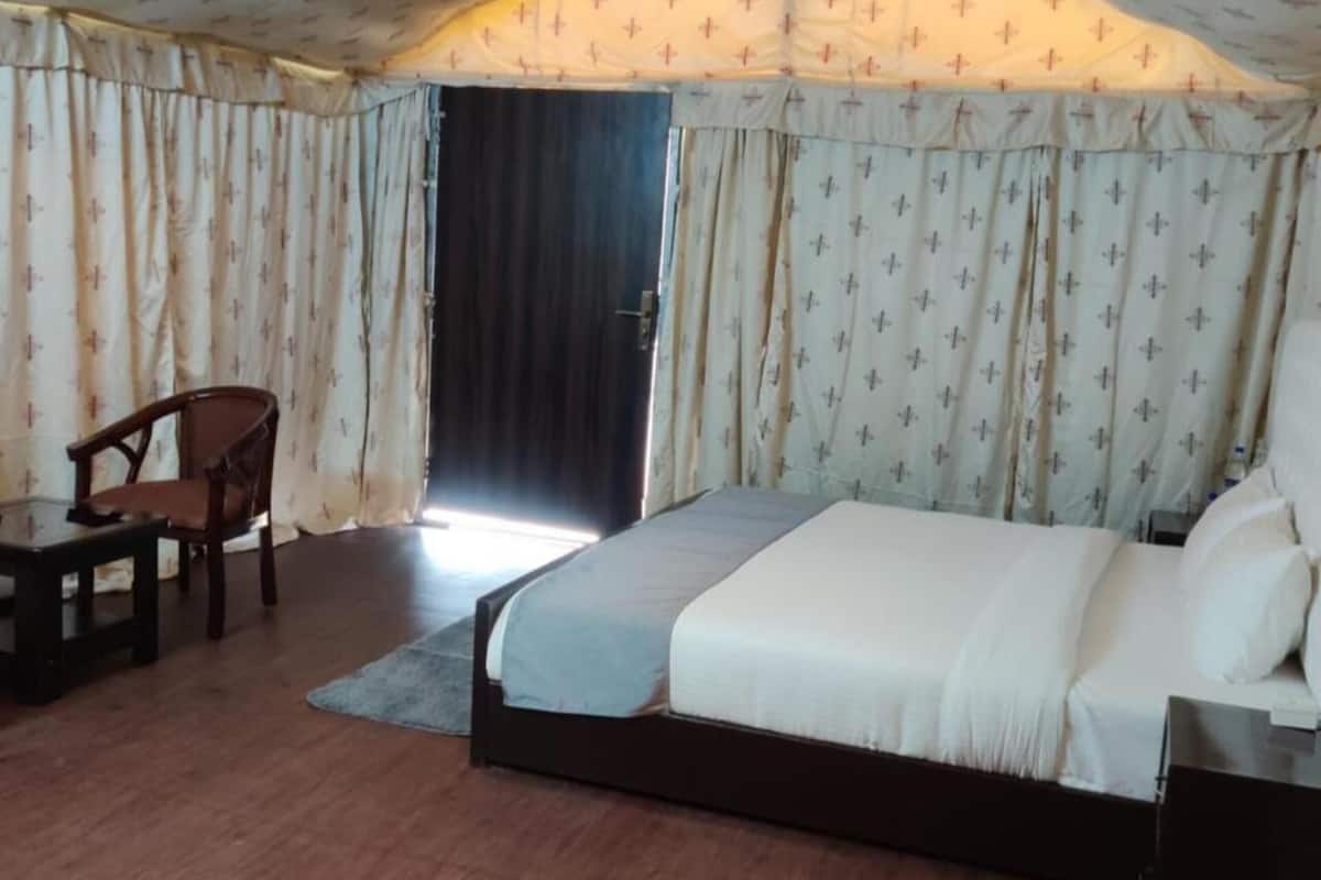 Ein Schlafzimmer mit Bett, Stuhl, Nachttisch und einer Tür, die nach draußen führt.