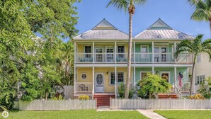 A two-story house with a white picket fence, a front porch, and a small garden. - A Key West State Of Mind at The Key West Golf Club (Key West)