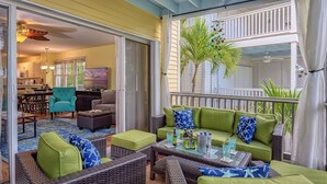 A cozy patio area with green cushioned seating, wicker furniture, and a glass table with drinks. - A Key West State Of Mind at The Key West Golf Club (Key West)