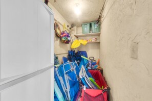 A narrow hallway with storage shelves, a white cabinet, and various bags and equipment.