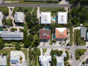 An aerial view of a residential area with houses, a swimming pool, and a road.