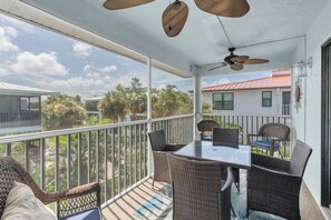 A covered outdoor area with wicker furniture, a table, and ceiling fans. - SeaDuction of Anna Maria Island (Holmes Beach)