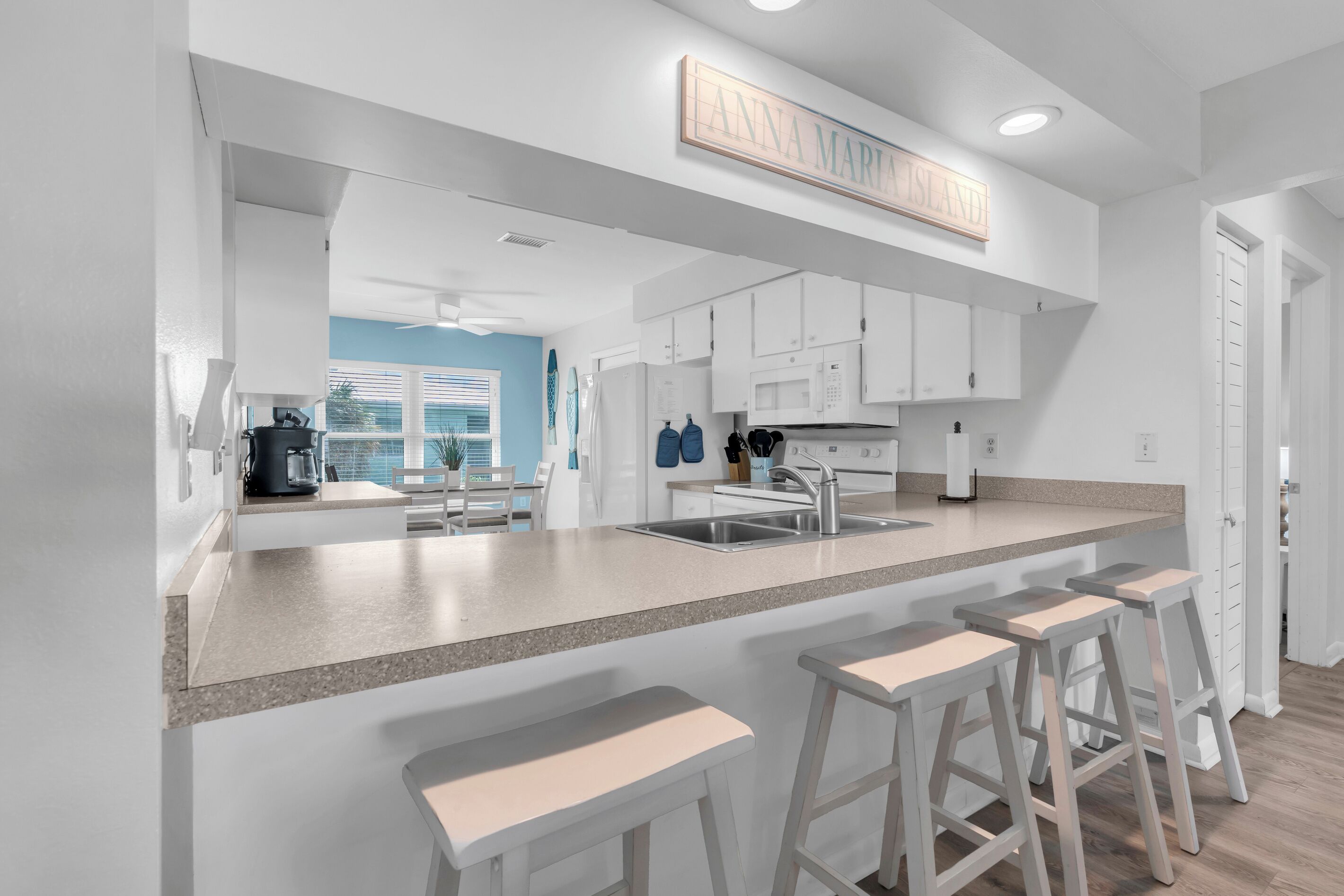 A modern kitchen with white cabinetry, a granite countertop, and a built-in island with bar stools.