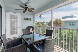 A balcony with wicker furniture, a ceiling fan, and a view of the surrounding area.