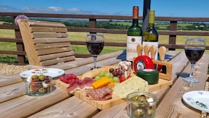 A picnic setup with a wooden table, a variety of cheeses, meats, and olives, accompanied by two bottles of wine and glasses. - Countryside Bungalow with private Hot Tub (Llansteffan (6.6miles N))