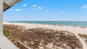 A beach with a clear sky, sandy shore, and sparse vegetation. - Beach House - Sky’s the Limit (Panama City Beach)