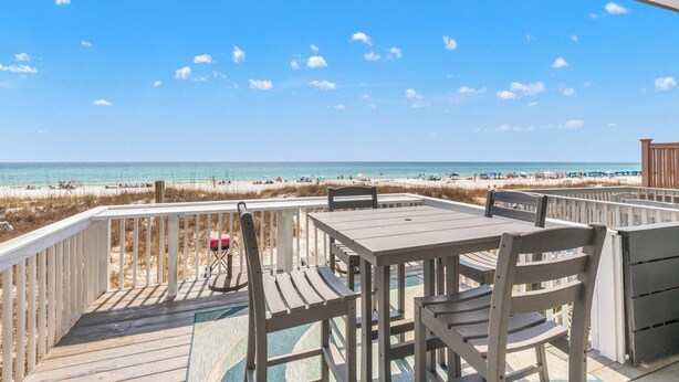 A wooden deck with a table and chairs overlooking a beach. - Beach House - Sky’s the Limit (Panama City Beach)