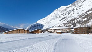 A snow-covered mountain with wooden buildings, a clear sky, and a ski trail. - La Bessannaise (Bessans)