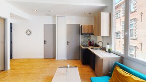 Una cocina moderna con armarios de madera, un horno empotrado y una ventana con vistas a un edificio de ladrillo.