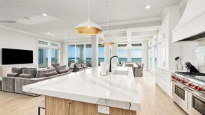 A spacious kitchen with a large island, modern appliances, and a view of the ocean. - Gulf-Front with Rooftop Deck, Theater and Pool (Miramar Beach)