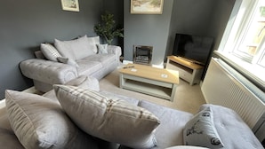 Un salon moderne avec un canapé gris, une table basse en bois et une cheminée.
