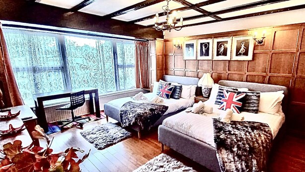 Une chambre avec deux lits, une grande fenêtre et un lustre.