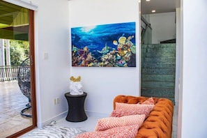 A modern living room with a large ocean-themed painting, a small statue, and a comfortable orange sofa.
