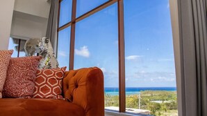 Ein Zimmer mit einem großen Fenster, das Meerblick und eine weite Landschaft zeigt.