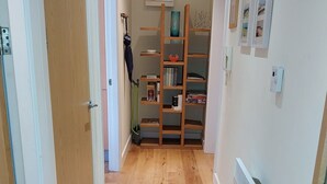 Un couloir doté d’un plancher en bois, d’une bibliothèque et d’un radiateur.