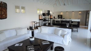 Un salon moderne avec un canapé blanc, une table basse foncée et un coin repas aux couleurs noir et blanc.