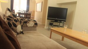 Un salon avec un canapé beige, une table basse en bois et un téléviseur à écran plat.