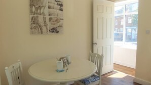 Un coin repas avec une table ronde, deux chaises et une porte donnant sur l’extérieur.