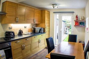 Een koelkast, een vaatwasser, kookgerei, borden en bestek