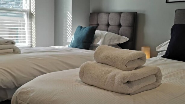 Ein Hotelzimmer mit zwei Betten, jeweils mit einem ordentlich gefalteten weißen Handtuch.
