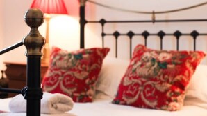 Ein Bett mit roten blumigen Kissen und einem schwarzen Metall-Kopfteil.