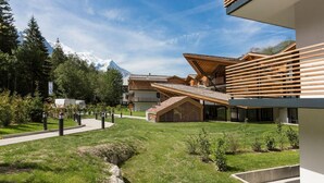 A modern building with a sloped roof and wooden beams, surrounded by a well-maintained lawn and trees. - Wifi, fitness, swimming pool, sauna, hammam, parking, tv, 34m², Chamonix (Chamonix-Mont-Blanc)