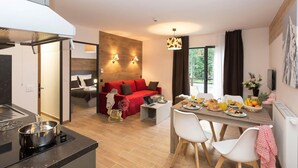 A modern hotel room with a kitchen, dining area, and a cozy seating area with a red sofa. - Wifi, fitness, swimming pool, sauna, hammam, parking, tv, 34m², Chamonix (Chamonix-Mont-Blanc)
