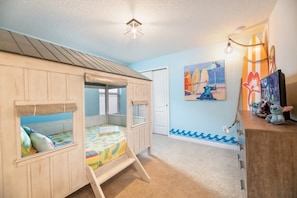 Cozy bedroom with a bunk bed setup, featuring a dresser and mirror, and a beach-themed painting.