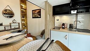 Una cocina moderna con estufa integrada, un lavabo y una cafetera. Hay una mesa de comedor con un mantel individual y cubiertos.