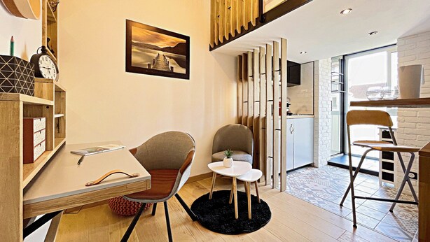 Una cocina moderna con techo de madera, una zona de comedor con mesa y sillas, y una encimera de cocina.