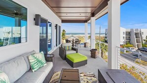 Ein überdachter Außenbereich mit einer Couch, Korbmöbeln und Blick auf den Strand.