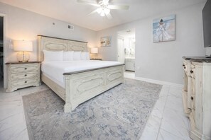 Un dormitorio con cama, mesitas de noche, ventilador de techo, un cuadro y cómoda.