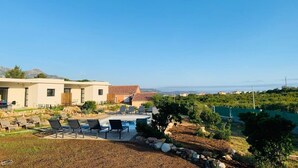 Una villa moderna con piscina, mobiliario exterior y vistas del paisaje circundante.