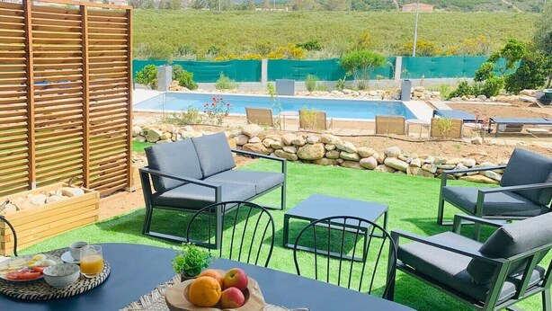 Un patio con piscina, mobiliario exterior y vistas a las montañas.