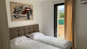 Ein Schlafzimmer mit zwei Betten, einem großen Fenster und einem Motorradbild an der Wand.